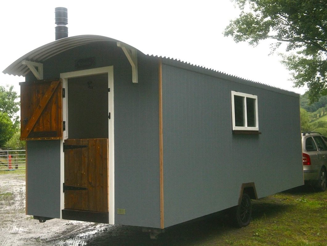 A grey-clad shepherd's hut with its doors open, ready for delivery.