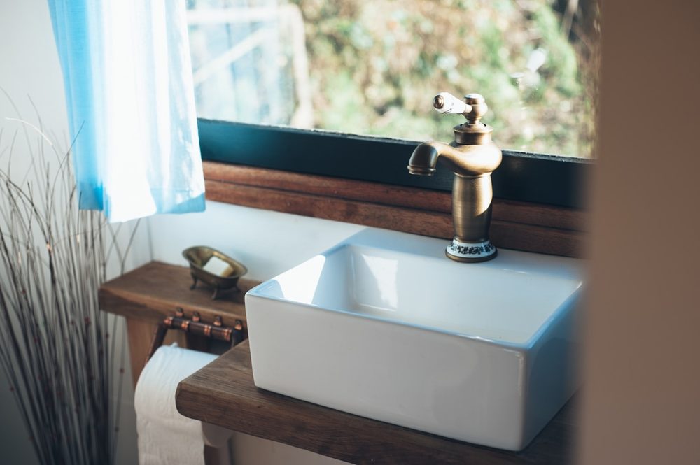 A brass tap and butler sink built into a timber washstand.