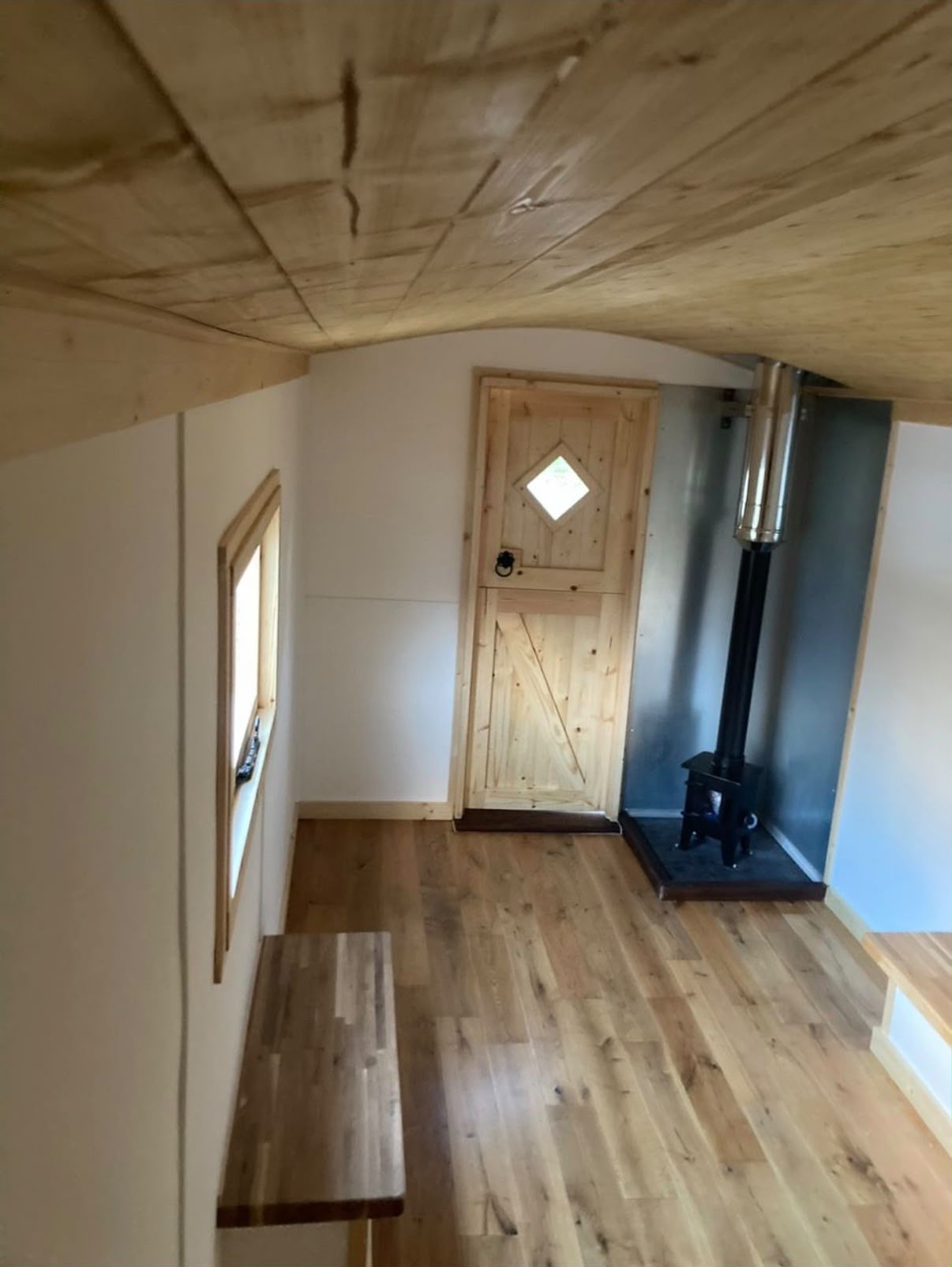Interior of a shepherd hut with a stable door, oak floor and wood burner.